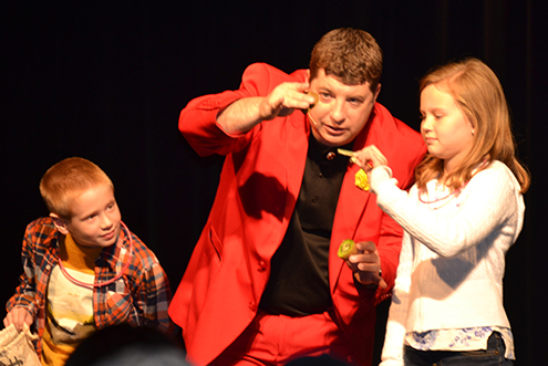 A man showing two kids some magic tricks