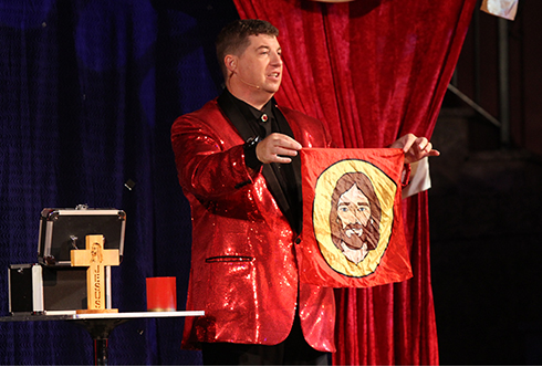A man holding a red cloth with a printed Jesus portrait